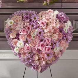 Heart-shaped standing spray of pink and lavender roses, carnations, and mums on an easel