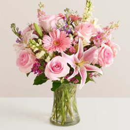Pink roses and lilies arranged in a clear glass vase