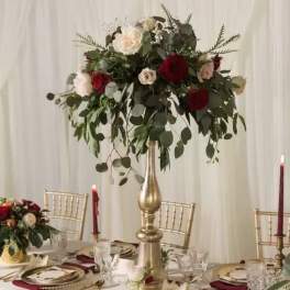 Tall floral centerpiece with red and white roses on a gold stand