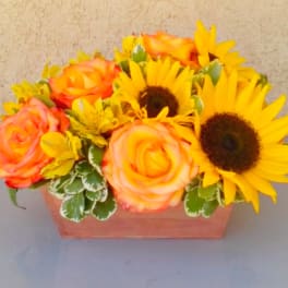 Orange roses and yellow sunflowers in a rectangular wooden container