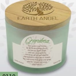 A green candle in a glass jar with a wooden lid labeled Earth Angel
