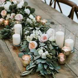 Floral table runner with white and blush blooms and glass candles