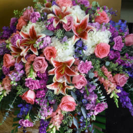 Large floral spray with pink roses, lilies, and purple flowers