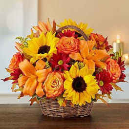 Basket of sunflowers, roses, and lilies in warm autumn colors