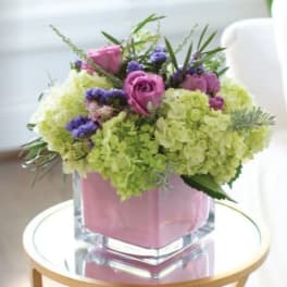Pink and purple bouquet in a clear square vase