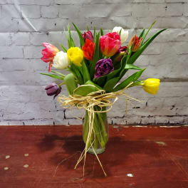 Colorful tulip bouquet in a glass vase with raffia tie