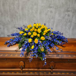 Yellow roses and blue flowers arranged on a wooden casket