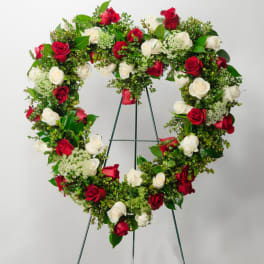Heart-shaped wreath of red and white roses on a stand