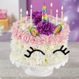Unicorn-themed cake decorated with flowers and lit candles