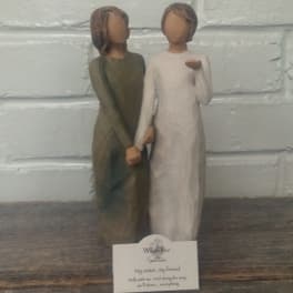 Two carved figurines standing side by side and holding hands