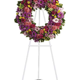 Circular floral wreath on a white easel with purple, pink, and yellow flowers