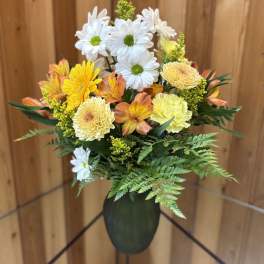 Bouquet of white daisies and yellow-orange flowers in a dark vase