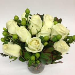 White rose bouquet in a glass vase with green berries