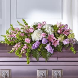 Pink and white floral casket spray with lilies, roses, and hydrangeas