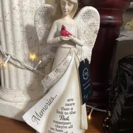 Angel figurine holding a red bird with a memorial message on the robe