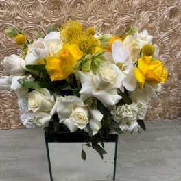 White and yellow floral arrangement in a square vase