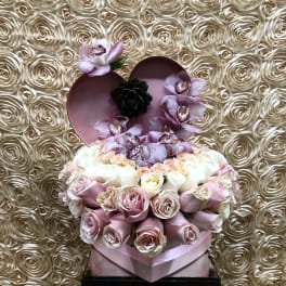 Heart-shaped box with pink roses and orchids on a rose-patterned backdrop