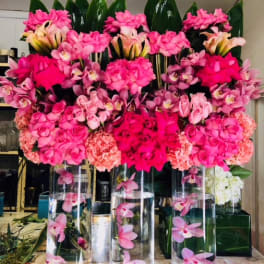 Pink floral arrangements in tall glass cylinders with orchids and roses