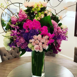 Tall bouquet of pink, purple, and white flowers in a glass vase
