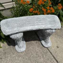 Stone bench with engraved text in front of orange flowers
