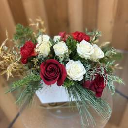 Red and white roses arranged in a clear round vase