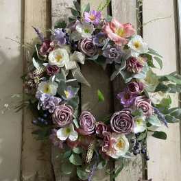 Floral wreath with pink, purple, and white blooms on a rustic wood background