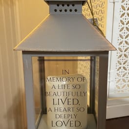 Gray memorial lantern with a candle and sympathy message