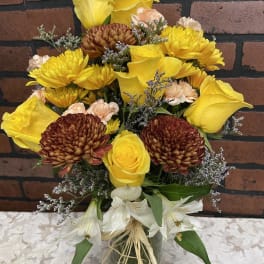 Yellow and white mixed bouquet with chrysanthemums and roses in a glass vase