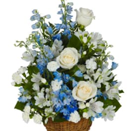 White roses and blue flowers arranged in a wicker basket