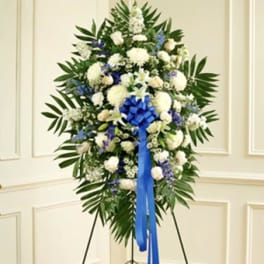 Standing floral spray of white and blue flowers with a blue ribbon