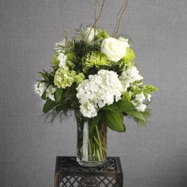 White and green floral arrangement in a clear glass vase
