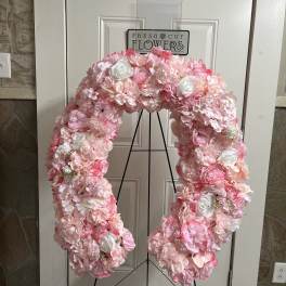 Pink and white floral wreath on a black stand