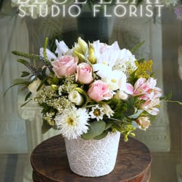 Mixed bouquet of pink and white flowers in a decorative white vase