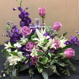 Purple and pink roses with white lilies around a clear cross