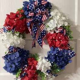 Patriotic wreath with red, white, and blue flowers and ribbon