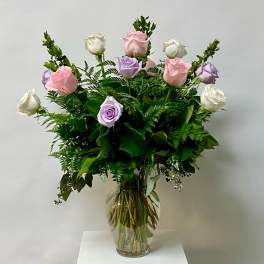 Bouquet of pink, lavender, and white roses in a clear glass vase