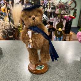 Plush teddy bear figurine on a wooden base with a graduation ribbon