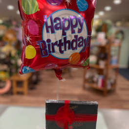 Birthday balloon with a box of chocolates tied below it