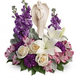 Purple and white floral arrangement with an angel figurine