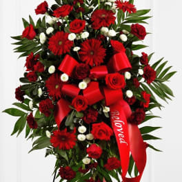 Standing spray of red roses and gerbera daisies with a red ribbon