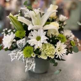 White lilies and daisies in a gray vase with a patterned ribbon
