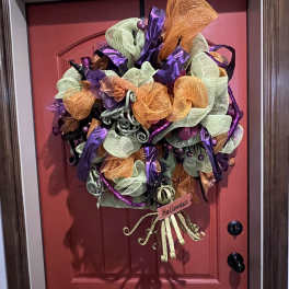 Halloween wreath with purple, orange, and green mesh on a red door