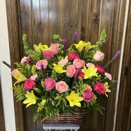Basket arrangement of pink roses, yellow lilies, and purple spikes