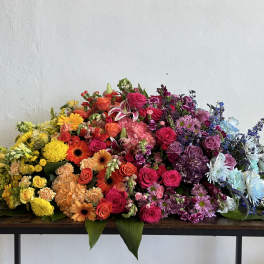 Large multicolored floral arrangement with roses, gerberas, and chrysanthemums on a table