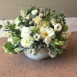White floral arrangement in a round white bowl vase