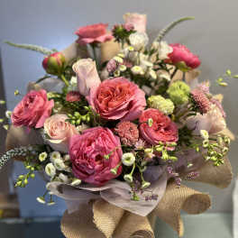 Bouquet of pink roses and small white flowers wrapped in burlap
