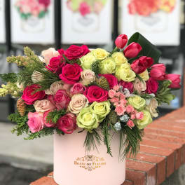 Mixed roses and tulips arranged in a pink hatbox