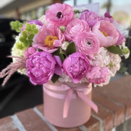 Pink bouquet in a round pink box tied with ribbon