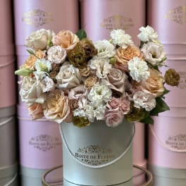 Pastel roses and carnations arranged in a round hatbox