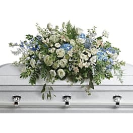 White and blue floral casket spray on a white coffin